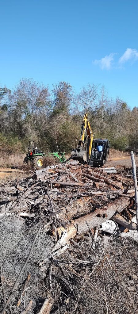 Tractor and excavator team cleaning up tree debris after cutting in Schley County, Ellaville