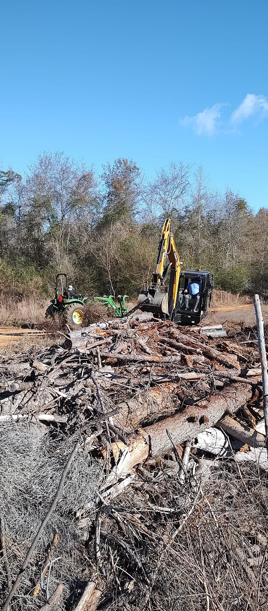 Tractor and excavator team cleaning up tree debris after cutting in Schley County, Ellaville